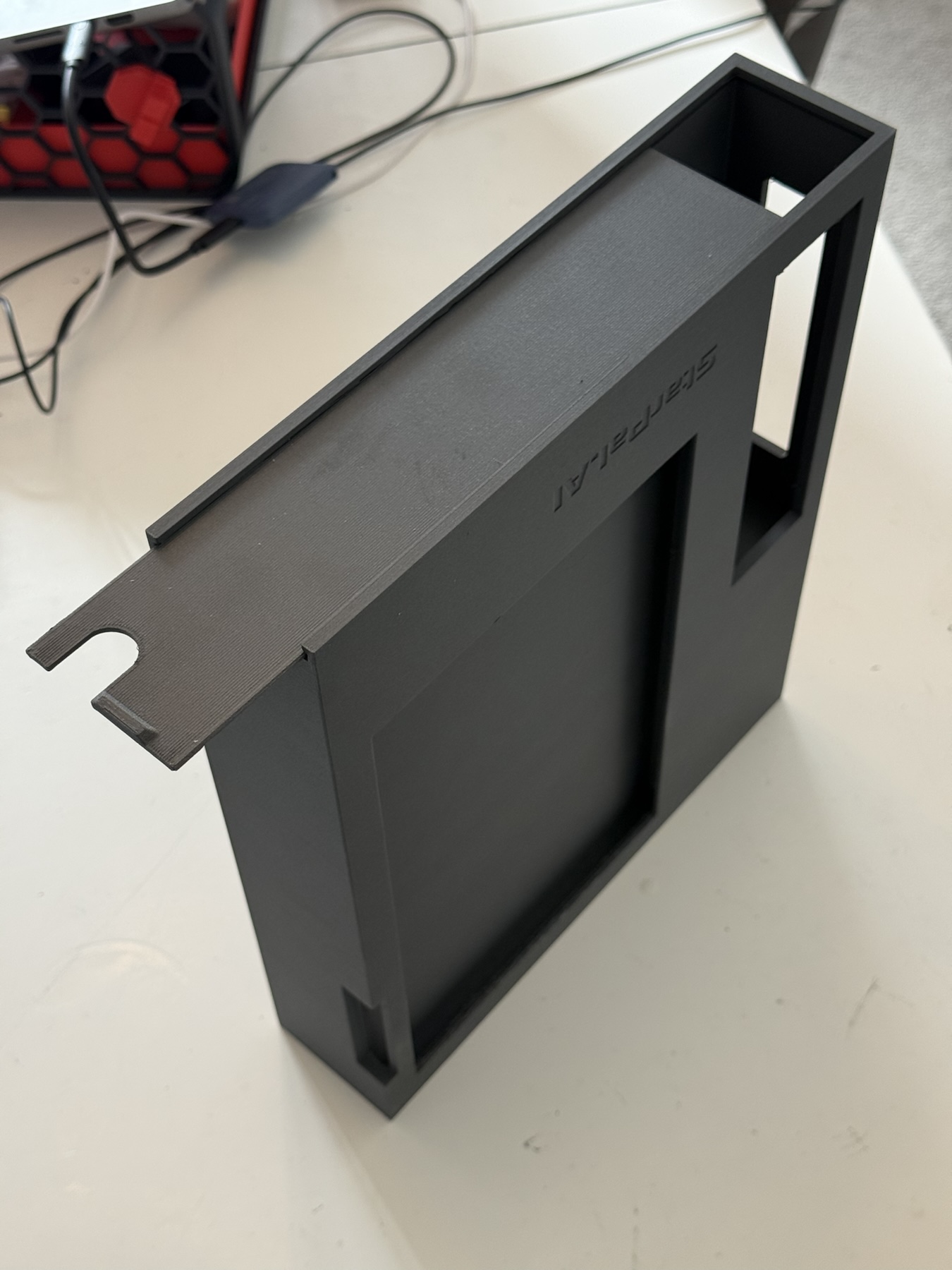 Black 3D printed enclosure and separate matching lid on a workbench